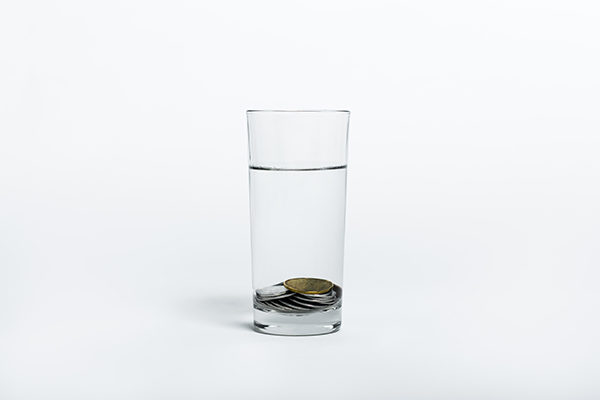 Ett glas med vatten, med mynt i botten av glaset.