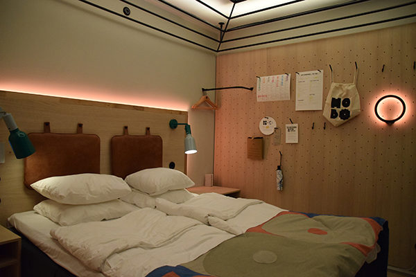 Hotellrum med två sängar och belysning bakom sänggaveln och i taket.