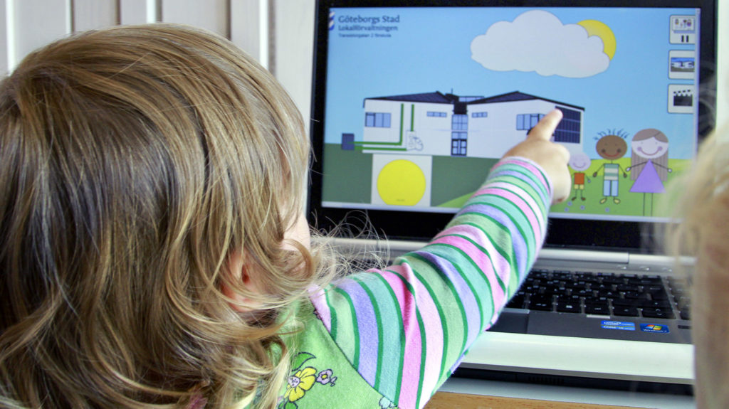 Ett barn som pekar på en datorskärm med ett hus som har solceller på taket.